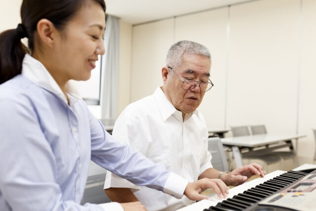 高齢者にピアノを教える女性