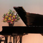 ステージに置かれたグランドピアノと花